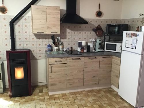 a kitchen with a white refrigerator and a stove at L’orée des fleurs in Rochechouart