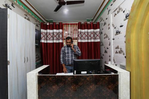 a man talking on a phone in a room with a computer at OYO Aradhya Residency in Bhubaneshwar