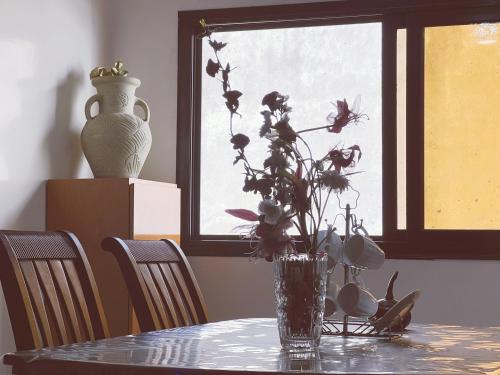 a vase with flowers on a table with a window at Villa soleil du Sénégal in Dakar
