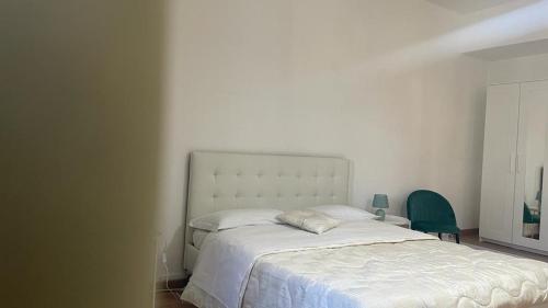 a bedroom with a white bed and a green chair at Doctor House standard, suites & luxury rooms in Enna