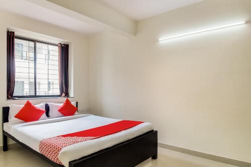 a bedroom with a bed with red pillows and a window at OYO Hotel Galaxy Near INOX in Yeraoda