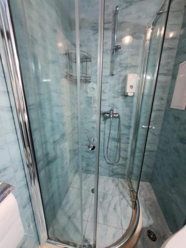 La salle de bains est pourvue d'une douche avec une porte en verre. dans l'établissement Апартамент Зимна приказка, à Chepelare