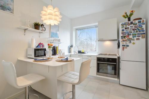 a white kitchen with a counter and a refrigerator at Ama Hyg Atelier Copenhagen-Cosy apt-in Copenhagen-near Airport- metro-beach in Copenhagen
