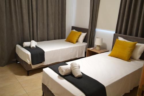 een slaapkamer met 2 bedden met gele en witte kussens bij Sweet Retreat in Paralimni