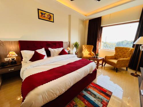 a bedroom with a bed and a chair and a window at Ganges blossam - A Four Star Luxury Hotel & Resort in Haridwār