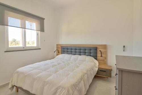 um quarto com uma grande cama branca e uma janela em Charming 4-Bed Villa in moncarapacho em Moncarapacho