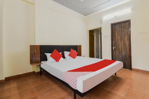 una camera da letto con un grande letto bianco con cuscini rossi di Super OYO Olive Grand a Patna