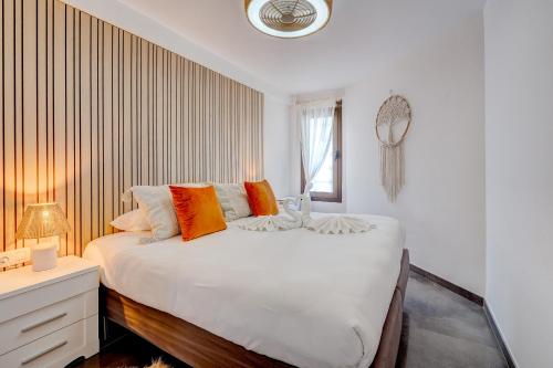 a white bedroom with a large bed with orange pillows at Sea Cocoon in Playa de las Americas