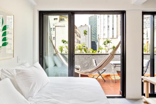 a bedroom with a bed and a hammock on a balcony at Tabas - Ed. Magdalena Laura - Vila Buarque in Sao Paulo