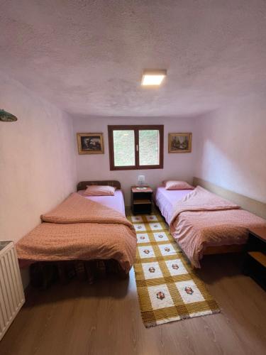 une chambre avec deux lits et une fenêtre dans l'établissement Gyimesi kulcsosház / Casa de vacanta Ghimes, à Lunca de Sus