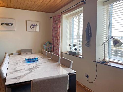 a dining room with a table and chairs and two windows at Apartment 235 Roundstone in Roundstone