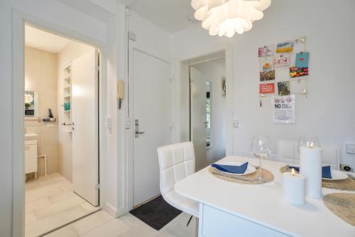 a white kitchen with a dining table and a chandelier at Copenhagen, Perfect apt. near the beach. in Copenhagen