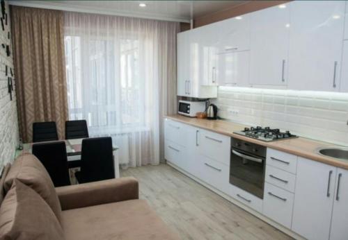 uma cozinha com armários brancos e um forno com placa de fogão em VIP APARTMENTs em Lutsʼk