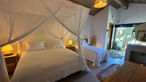 1 dormitorio con cama blanca y espejo en Pousada Hayo Pé na Areia en Caraíva