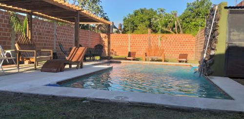 una piscina con sillas y una pared de ladrillo en La Chiqui - Quinta - Alquiler Temporario en Formosa