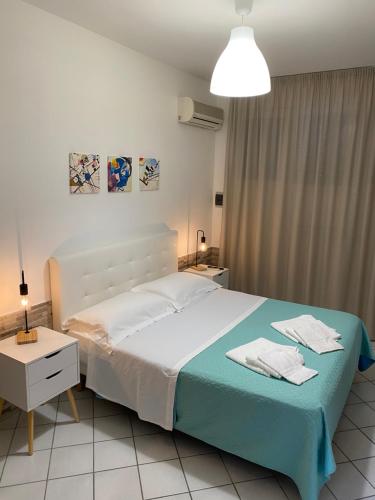 een slaapkamer met een wit bed en een blauwe deken bij Casa vacanza Scala dei Turchi in Realmonte