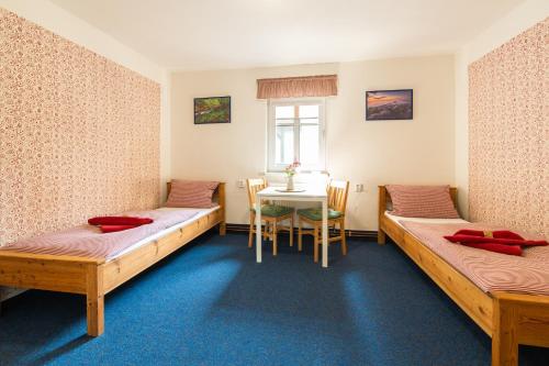 a room with two beds and a table in it at Penzion Na Výšinkách, Jetřichovice, České Švýcarsko in Jetřichovice