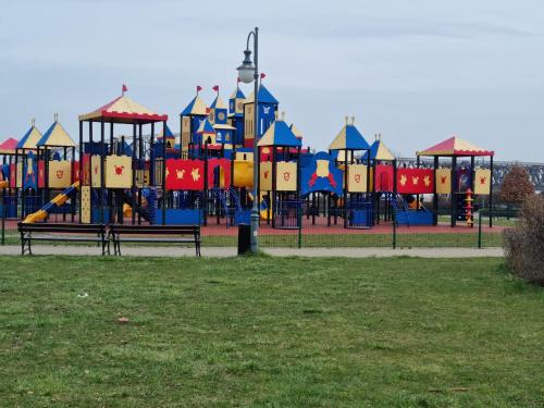 Un colorido patio de juegos en un parque con dos bancos. en Apartament Nad Wisłą, en Tczew