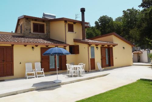 un patio con sillas y una sombrilla frente a una casa en B&B Villa Del Regno en Centola