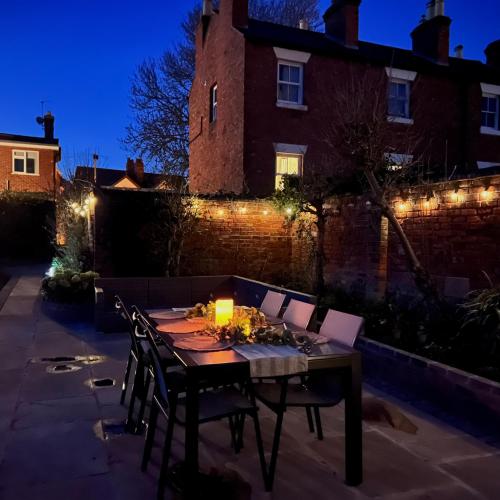 a table with chairs and a candle on a patio at Quaint Georgian house with Parking & Huge Garden 10 mins walk from town in Shrewsbury