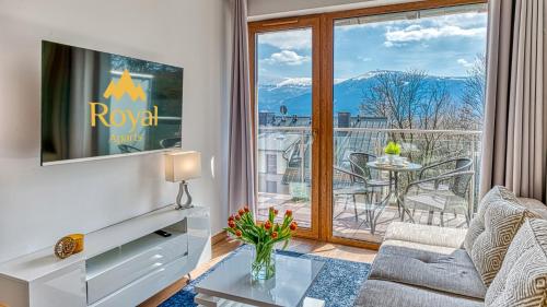 ein Wohnzimmer mit einem Sofa, einem TV und einem Balkon in der Unterkunft Apartamenty ROYAL APARTS VIP Widok 800 - z panoramą gór in Szklarska Poręba