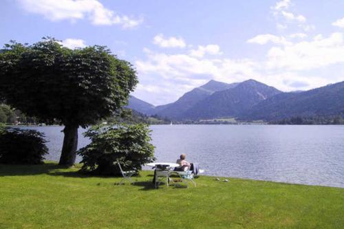 Ein Mann, der an einem Picknicktisch am See sitzt. in der Unterkunft Ferienwohnungen am See - Hinterseer in Schliersee