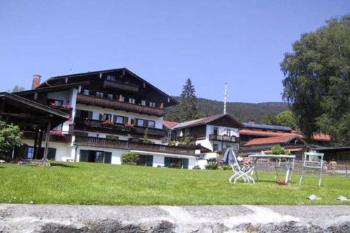 ein großes Gebäude mit einem Tisch und Stühlen im Gras in der Unterkunft Ferienwohnungen am See - Hinterseer in Schliersee