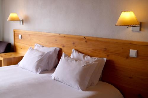 a bedroom with a bed with white pillows and two lamps at Casas Goulart in Canto da Areia