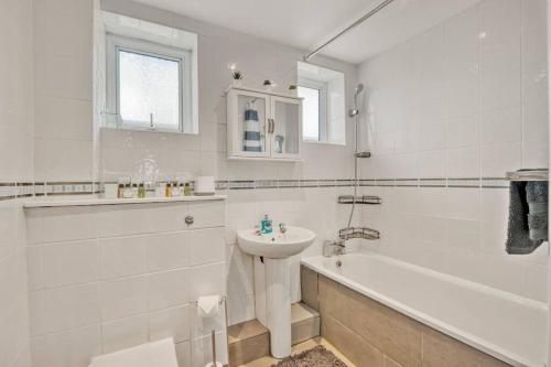 Lovely 3-Bed Clapham Common في لندن: حمام أبيض مع حوض وحوض استحمام