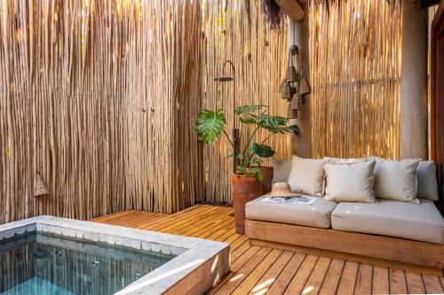 un sofá sentado en una terraza junto a una piscina en Pousada Hayo Pé na Areia en Caraíva