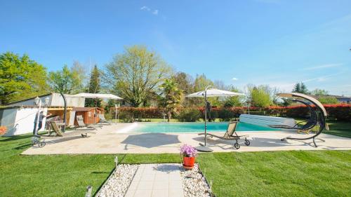 een achtertuin met een zwembad met een schommel bij Villa de vacances moderne à côté de Bergerac in Prigonrieux