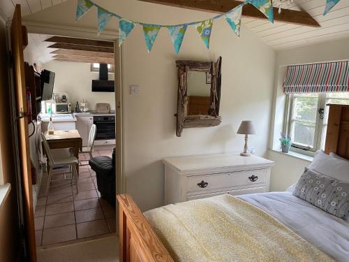 a bedroom with a bed and a table and a kitchen at Dairy Cottage Luxury B&B in Attleborough