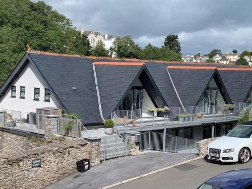 a house with a black roof and a car parked in a parking lot at Beautiful, spacious 3 bed Brixham apartment in Brixham