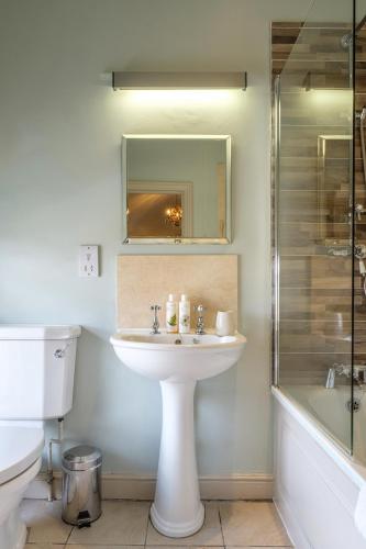 a white bathroom with a sink and a shower at The Black Lion, Long Melford in Long Melford
