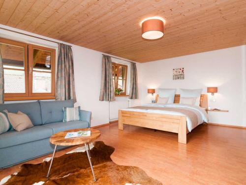 ein Schlafzimmer mit einem Bett und einem blauen Sofa in der Unterkunft Ferienwohnungen Nutz in Bad Wiessee