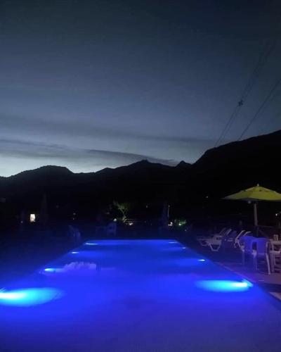 a swimming pool with blue lights at night at Pousada Sítio da Floresta in Sana