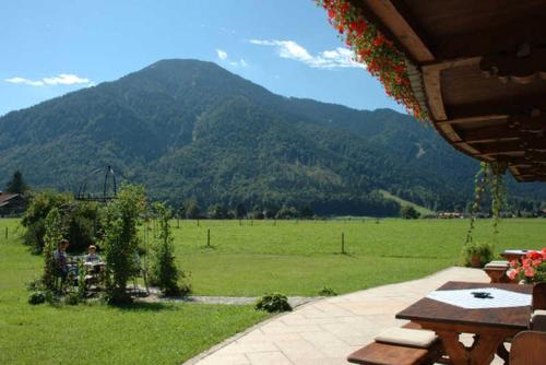 a patio with a view of a field and mountains at Gaestehaus Webermohof in Rottach-Egern