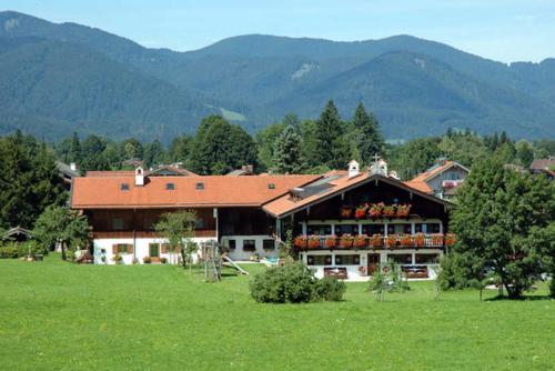 a building in a field with mountains in the background at Gaestehaus Webermohof in Rottach-Egern