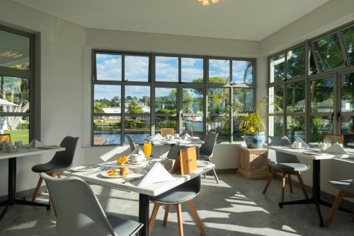 a dining room with tables and chairs and windows at St. James of Knysna in Knysna