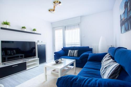 sala de estar con sofás azules y TV en El Mirador de Mundaka by Urdaibai Rentals, en Mundaka