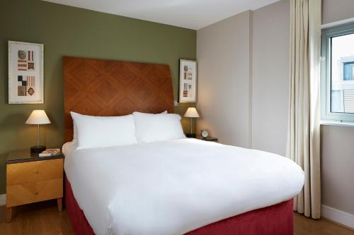 duże białe łóżko w pokoju z oknem w obiekcie Marlin Aldgate Tower Bridge w Londynie