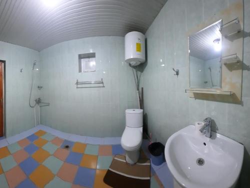 a bathroom with a white toilet and a sink at JANS дача in Chimgan