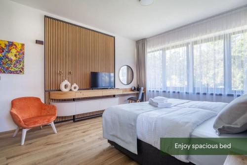 a bedroom with a bed and a chair and a television at Vista Resort & Club in Prague