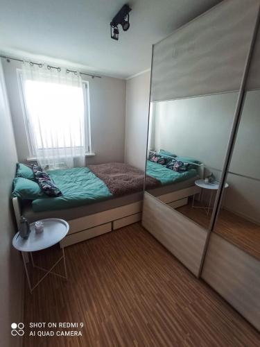 a small bedroom with a bed and a mirror at Apartament boBoski in Wadowice