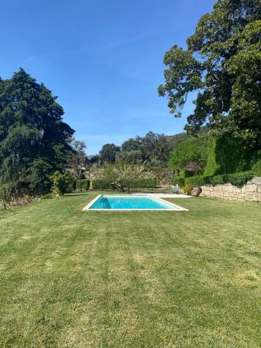a swimming pool in the middle of a grass field at Quinta da Porta - Solar de Vale de Prazeres in Vale de Prazeres