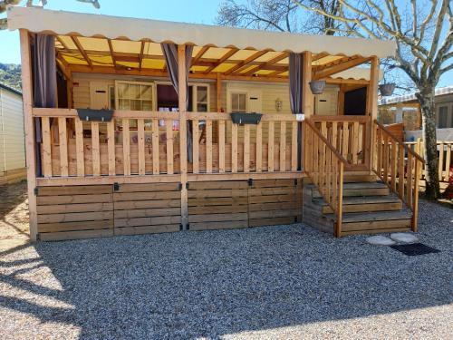 eine Holzhütte mit einer Veranda und einer Holztreppe in der Unterkunft Mobil-home camping 