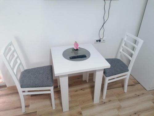 a white table with two chairs and a remote control on it at Apartmani Ružina staza in Rudnik Kačerski