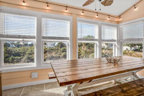 a dining room with a wooden table in front of windows at Harbor Island 2 Ebb Tide Ct in Oceanmarsh Subdivision