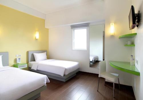 a hotel room with two beds and a desk at Amaris Hotel Panakkukang in Makassar