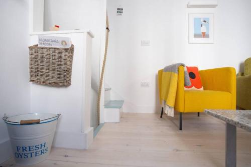 a living room with a yellow chair and a table at Sandpiper Cottage By The Sea. Broadstairs. in Kent